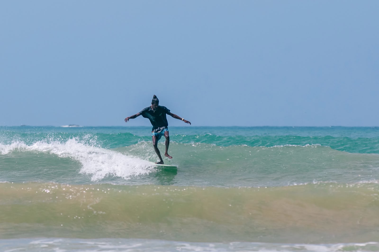 Achi riding along a clean green wave